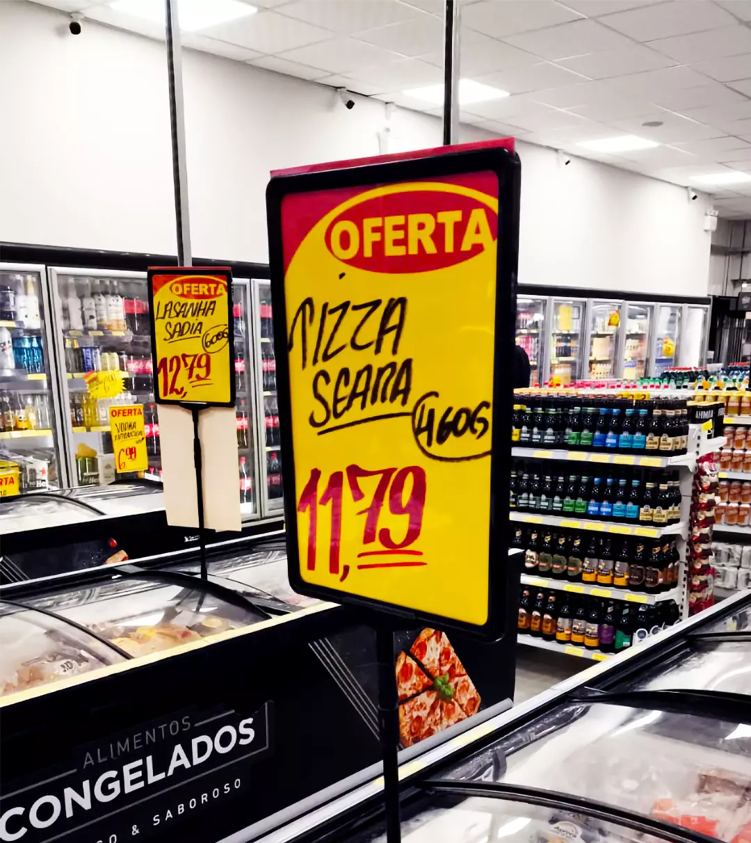 Cartaz de oferta feito à mão em setor de congelados de supermercado, ilustrando a precificação manual no pequeno varejo alimentar.