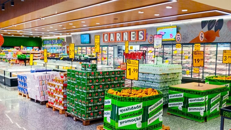 Supermercado com pedestal porta-cartaz posicionado ao lado de produtos em oferta, otimizando a comunicação no PDV com clareza e destaque.