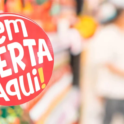 Sinalização vermelha com os dizeres “Tem Oferta Aqui!” destacando promoção em gôndola de supermercado, representando a exposição estratégica de ofertas.
