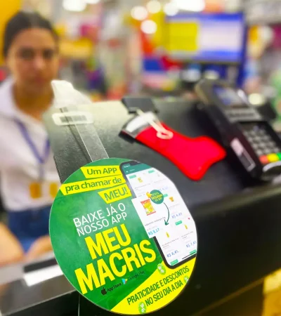 Comunicação Visual no Caixa: Incentivo à Fidelização e Engajamento Display de comunicação visual no caixa de supermercado divulgando aplicativo de fidelidade, representando estratégia de engajamento no varejo alimentar.