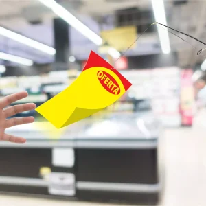 Mão tentando alcançar um cartaz amarelo e vermelho com a palavra “OFERTA” pendurado em uma vara de pescar, representando a dificuldade de manter as vendas após a Black Friday.