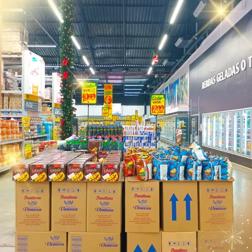 Exposição de produtos natalinos no supermercado com ilhas promocionais Expositor com panetones e produtos natalinos posicionados no centro de um supermercado decorado para o Natal.