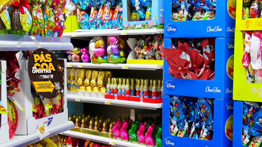 Gôndola de supermercado com produtos de Páscoa variados como ovos e coelhos de chocolate organizados para impulsionar vendas sem depender apenas de chocolate.